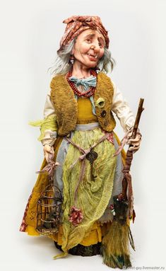 a statue of an old woman holding a broom and wearing a hat with feathers on it