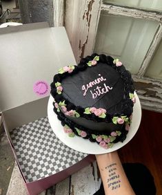 a heart shaped cake sitting on top of a table next to a box with writing on it