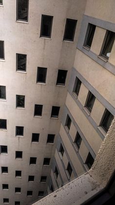 looking up at the side of a tall building with lots of windows on each floor