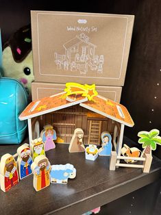 a nativity scene with figurines in front of it and an open cardboard box