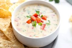 a white bowl filled with dip surrounded by tortilla chips