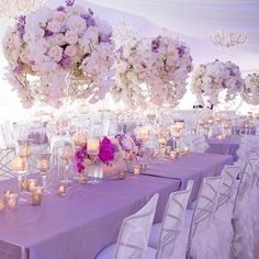 the tables are set with white and purple flowers in vases, candles and centerpieces