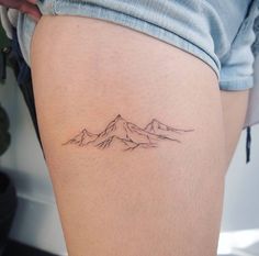 a woman's thigh with a mountain tattoo on it