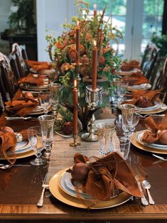 a table set with plates, silverware and candlesticks for thanksgiving dinner party