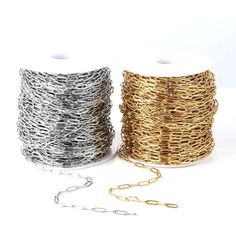 two spools of gold and silver wire next to each other on a white background