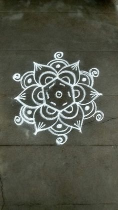 a sidewalk that has some white chalk on it with a flower design drawn on it