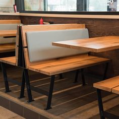 some tables and benches in a restaurant with wood flooring on one side and black metal legs on the other