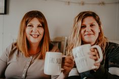 two women holding coffee mugs in their hands