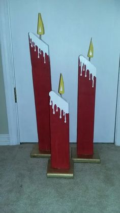 two tall red candles with white icing on them sitting in front of a door