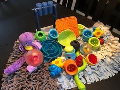 there are many different toys on the table together, including plastic cups and spoons