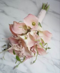 a bouquet of pink flowers sitting on top of a white marble countertop with greenery