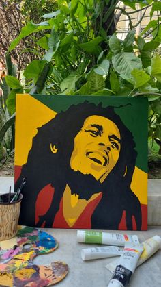 a painting of bob marley on a table next to paintbrushes and other art supplies