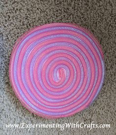 a pink and purple basket sitting on top of a carpet next to a white wall