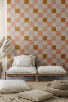 a living room with two couches and pillows on the floor in front of a checkered wall