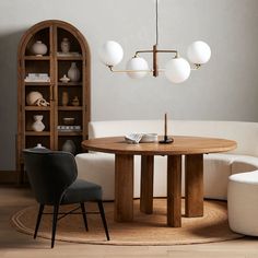 a living room with a round table surrounded by white chairs and bookshelves in the corner