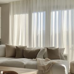 a living room filled with lots of white furniture and pillows on top of a couch