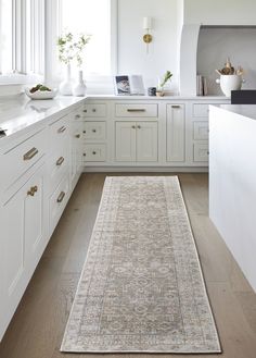 a large rug in the middle of a kitchen with white cabinets and countertop space