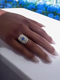 a woman's hand with a diamond and blue ring on top of her finger