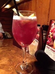 a person holding up a drink in front of a book on a table with other items