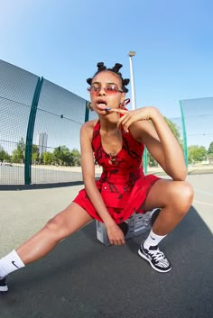 a woman sitting on top of a tennis court holding a racquet in her mouth