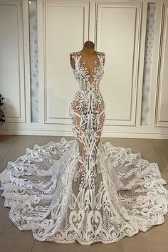 the back of a white wedding dress on display in front of a wall and floor