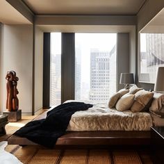 a large bed sitting in the middle of a bedroom next to a tall glass window