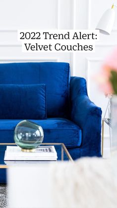 a blue couch sitting in a living room next to a white table with a vase on it