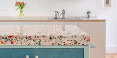 a kitchen island covered with a floral tablecloth next to a sink and stove top