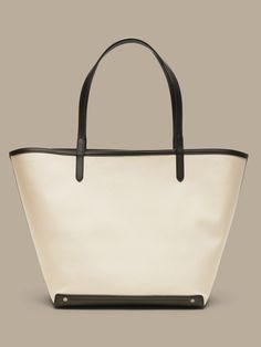 An elegant companion to everyday style, this classic tote goes anywhere with ease with spacious storage, sturdy leather trim, and a snap closure.  Sturdy leather handles.  Open top with snap closure.  Height: 16" (41cm) Width: 25" (63cm) Depth: 8" (2 Classic Large Capacity Bucket Bag For Everyday, Everyday Coated Canvas Bags With Handles, Canvas Bucket Bag With Leather Trim Tote, Classic Coated Canvas Shoulder Bag, Canvas Bucket Bag With Leather Handles For Everyday Use, Canvas Shopping Bag With Leather Top Handles, Canvas Shopping Bag With Leather Handles, Top Handle Canvas Bag With Leather Handles For Shopping, Canvas Shopping Bag With Double Leather Handles