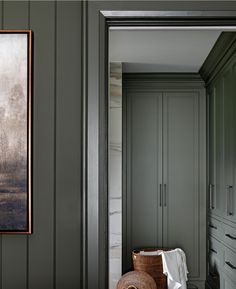 a painting hangs on the wall next to a chair in a room with green walls