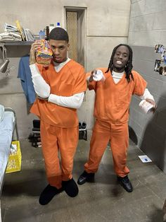 two men dressed in orange prison uniforms standing next to each other, one holding a bag