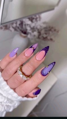 a woman's hand with purple and pink nail polishes on her nails, in front of a mirror