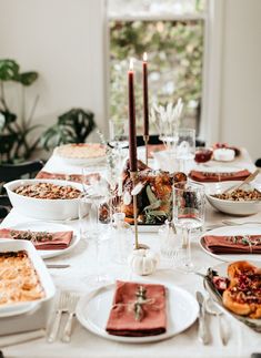 a table set with plates, silverware and candles on it for a festive dinner