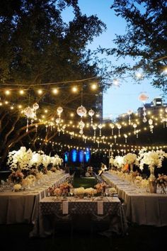 an outdoor dining area with lights strung over the tables and flowers on the tablecloths