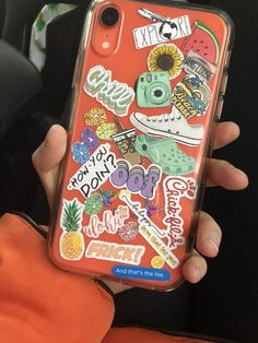 someone holding up their phone case with stickers on it