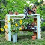 a garden bench made out of wooden pallets with potted plants and flowers on it