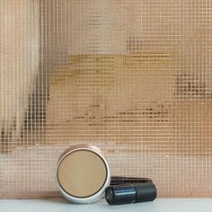 three different types of cosmetics sitting on a counter next to a wall covered in mesh