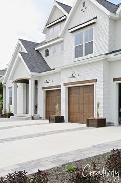 a white house with two brown garage doors