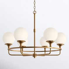 a brass chandelier with five white glass balls hanging from the center and four arms