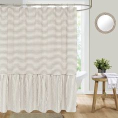 a white and black shower curtain in a bathroom next to a table with a potted plant