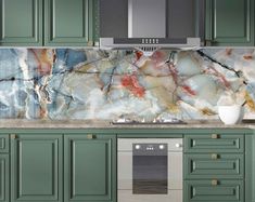 a kitchen with green cabinets and marble backsplash, stainless steel range hoods