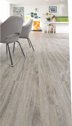 a living room with grey wood flooring and chairs