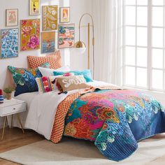 a bed with colorful comforters and pictures on the wall