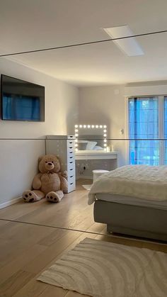 there is a teddy bear sitting on the floor in front of a bed with mirrored walls