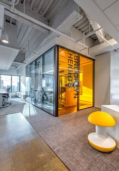 an empty office with glass walls and yellow accents on the front entrance to the room