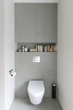 a white toilet sitting in a bathroom next to a wall mounted book shelf filled with books