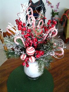 a vase filled with candy canes and christmas decorations on top of a wooden table