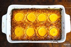 a casserole dish filled with oranges on top of a wooden table