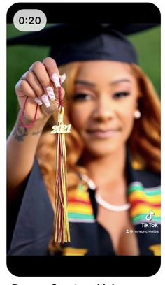 a woman in graduation gown holding up a tassel