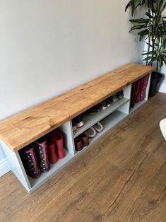 a wooden bench sitting on top of a hard wood floor next to a potted plant